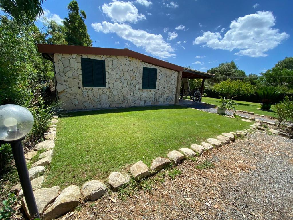 uma casa de pedra com um quintal com um relvado em Casa Chia a 5 minuti dal mare - Su Giudeu Tuerredda em Chia