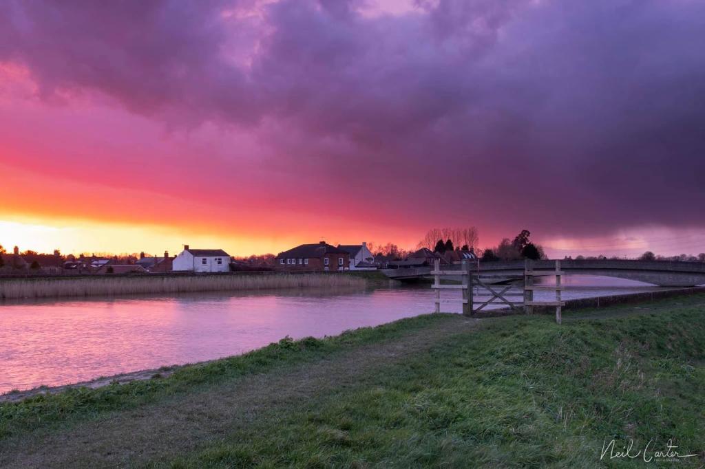 a sunset over a body of water with a bridge at Riverbank Guest House in Wiggenhall Saint Germans