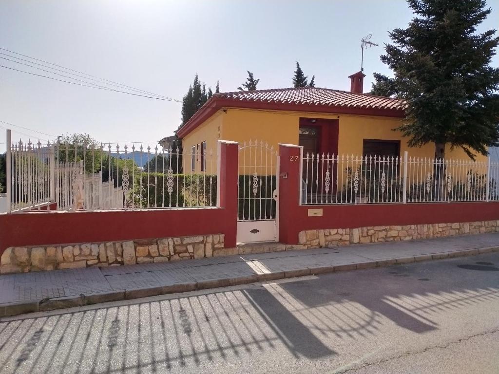 une maison jaune et rouge avec une clôture dans l'établissement Ca l'Aiguadora, à Sant Mateu