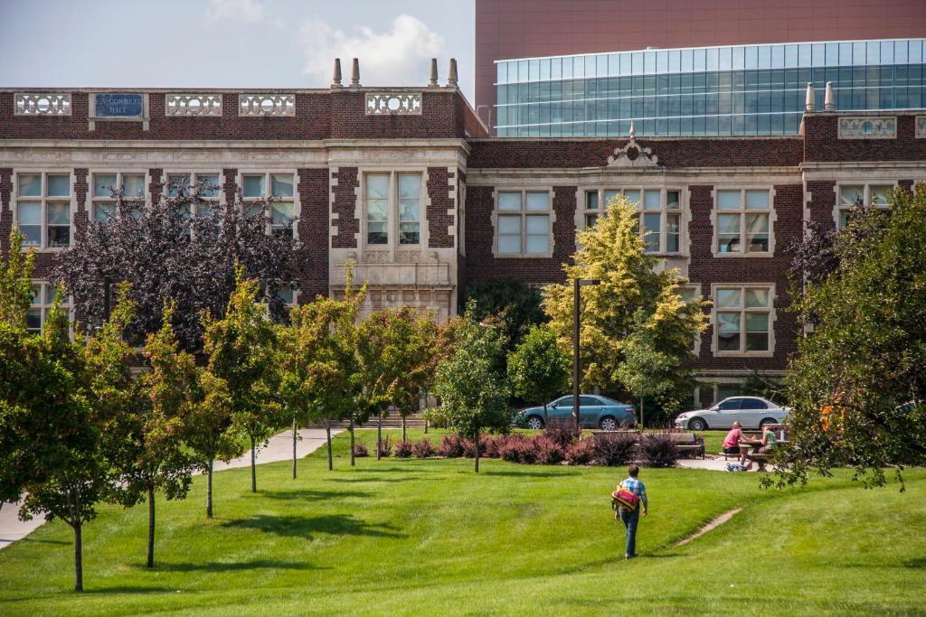 une personne debout dans l'herbe devant un bâtiment dans l'établissement University of Alberta - Hotel, à Edmonton