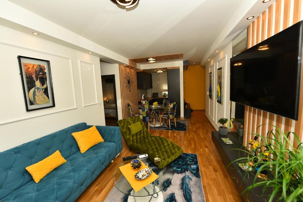 ein Wohnzimmer mit einem blauen Sofa und einem TV in der Unterkunft Grand Lux apartman in Čačak