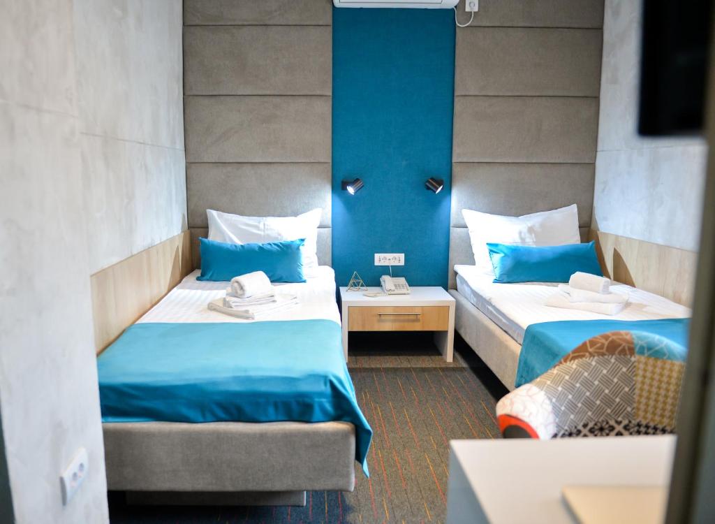 2 camas en una habitación con paredes azules en Garni hotel King en Kragujevac