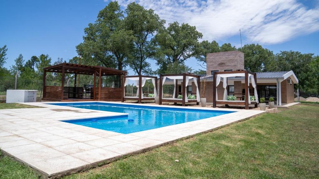 a swimming pool with a gazebo and a house at FRAMA Cabañas del Lago in Potrero de Garay