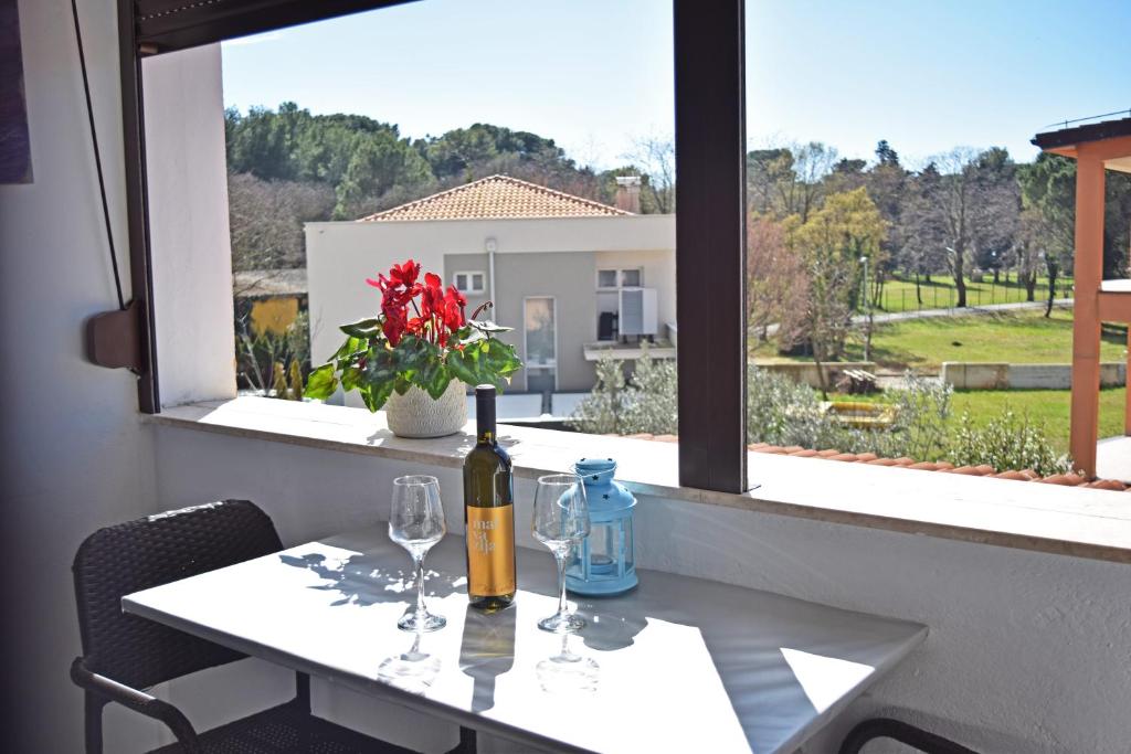 a table with a bottle of wine and two glasses at Apartmenthaus Mira Eldic in Fažana