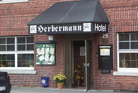 un panneau indiquant un hôtel à l'avant d'un bâtiment en briques dans l'établissement Hotel Alex Herbermann, à Glandorf