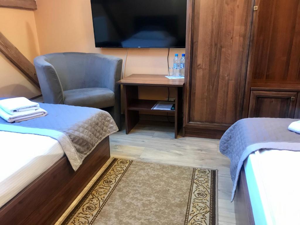 Habitación pequeña con silla, escritorio y TV. en Hotelik Polonia, en Łowicz