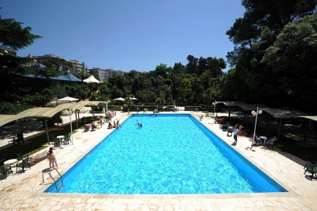 a large blue swimming pool with people sitting around it at Hotel Villa Rosa in Martina Franca