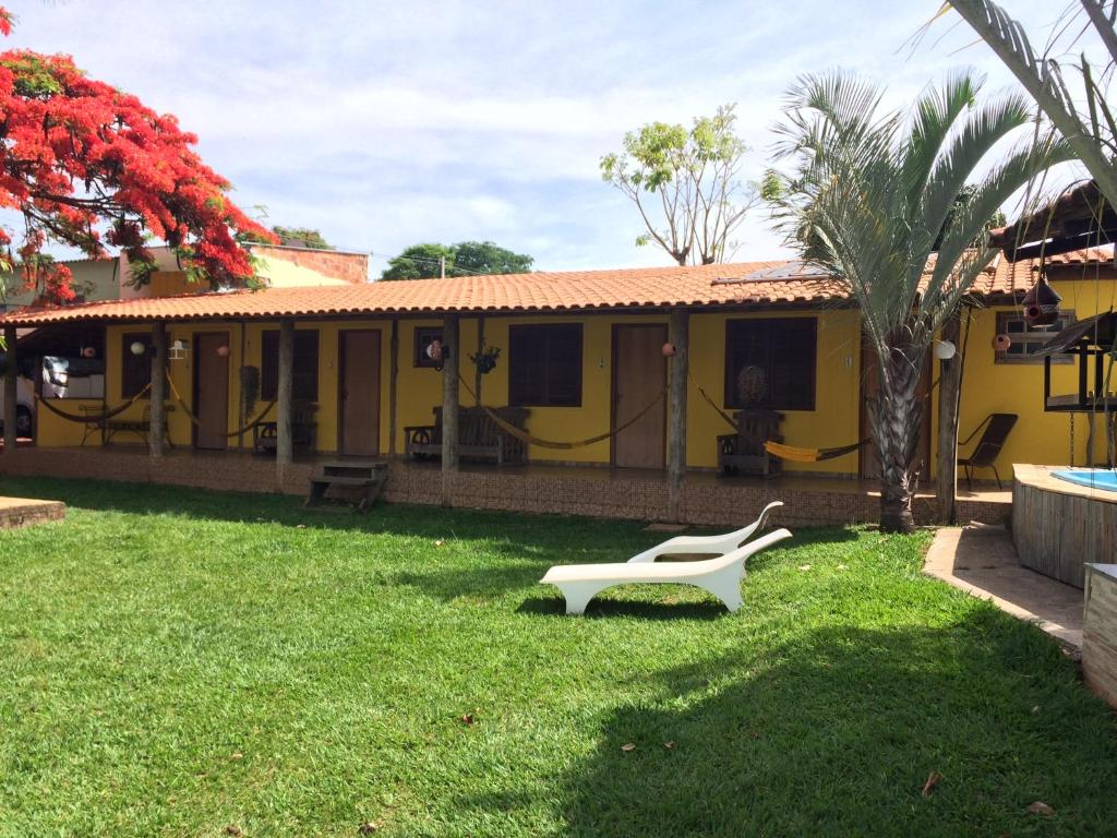 una casa gialla con una panchina bianca nel cortile di Pousada e Restaurante do Porto a São João Batista do Glória