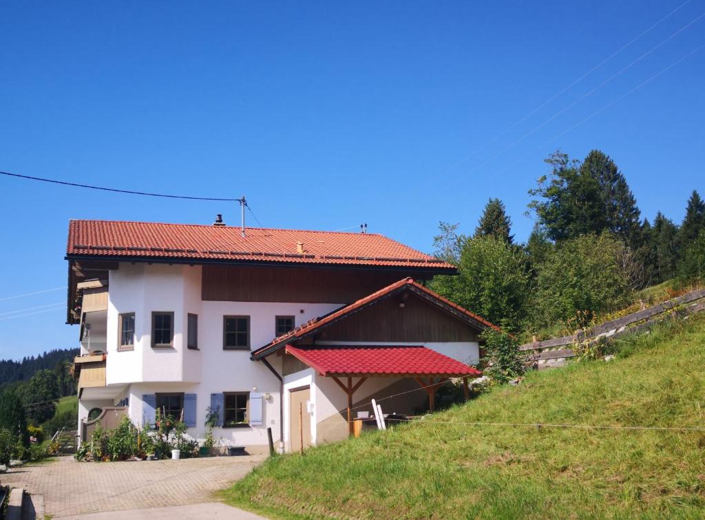 ein weißes Haus mit rotem Dach auf einem Hügel in der Unterkunft Jungholz Erlebnis in Jungholz