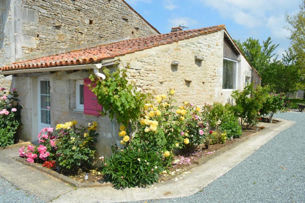 uma casa de pedra com flores em frente em Gîte Les Tilleuls em Beurlay