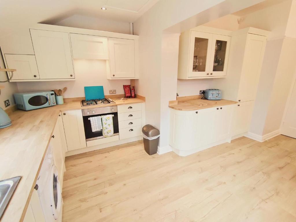 uma cozinha com armários brancos e piso em madeira em The Bays em Bridlington