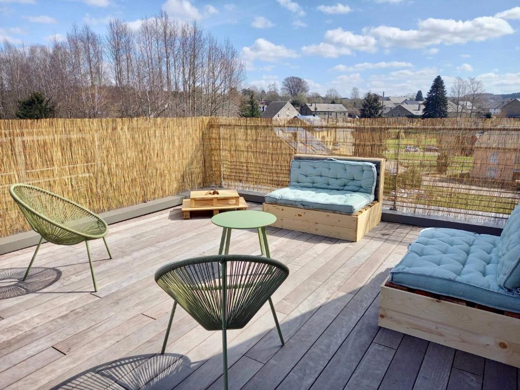 een patio met stoelen, een bank en een tafel bij Le grenier de Charlotte in Libin