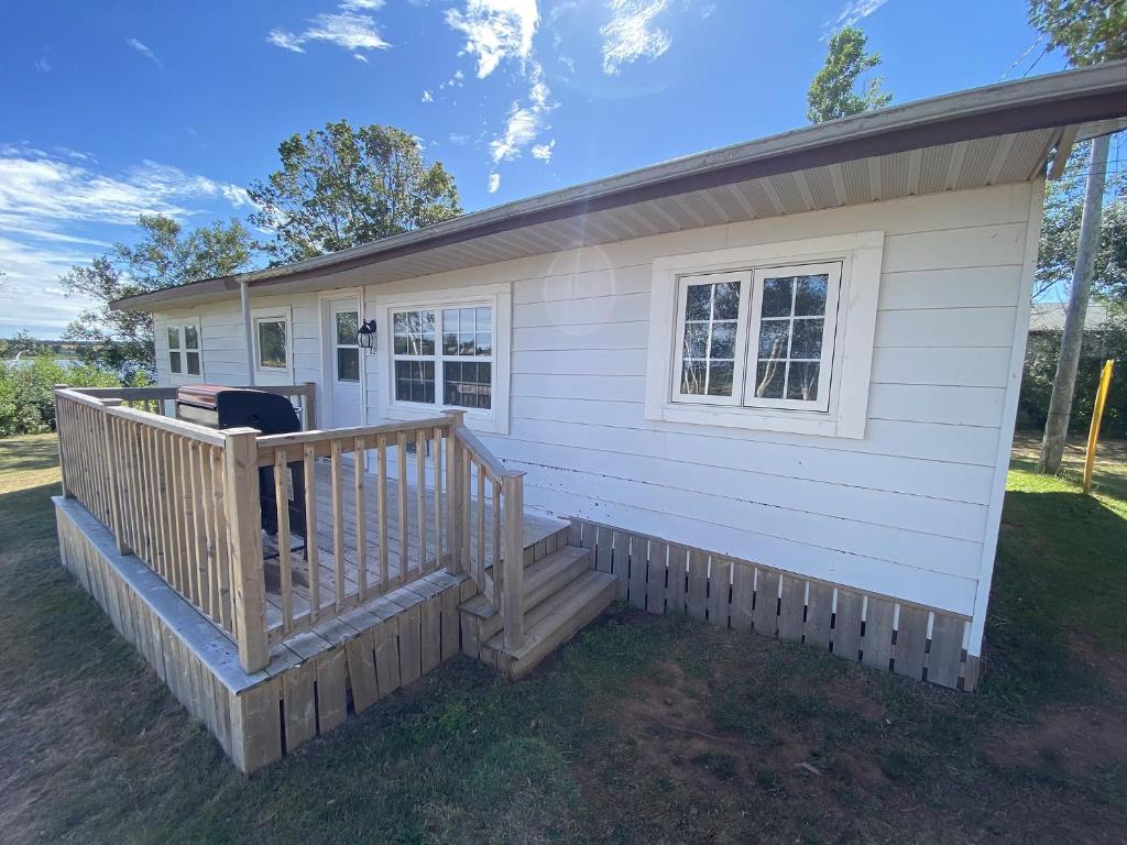 a tiny house with a porch and a deck at The Pines Motel and Cottages in Rustico