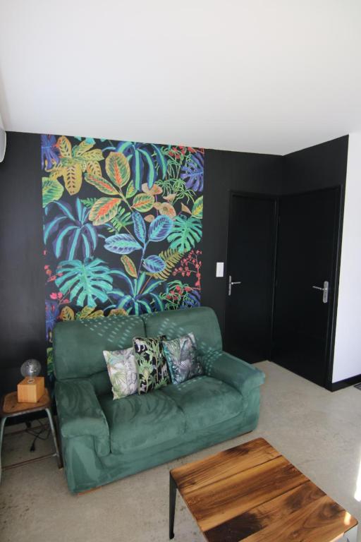 - un salon avec un canapé vert et un mur coloré dans l'établissement Cottages de la ville Daniou, à Langrolay