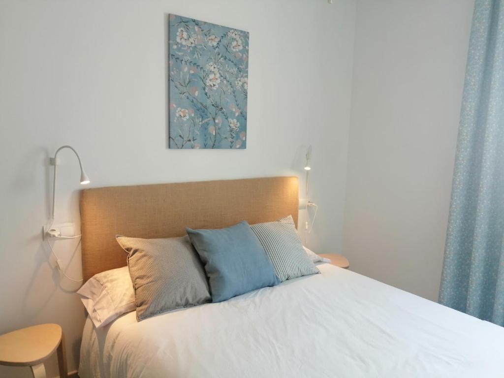 ein Schlafzimmer mit einem weißen Bett mit blauen Kissen in der Unterkunft Estudio Porto in San José