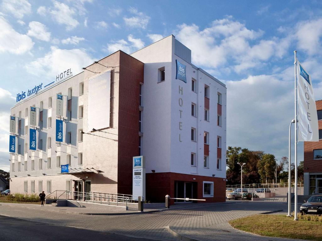 a large white building in a parking lot at ibis budget Torun in Toruń