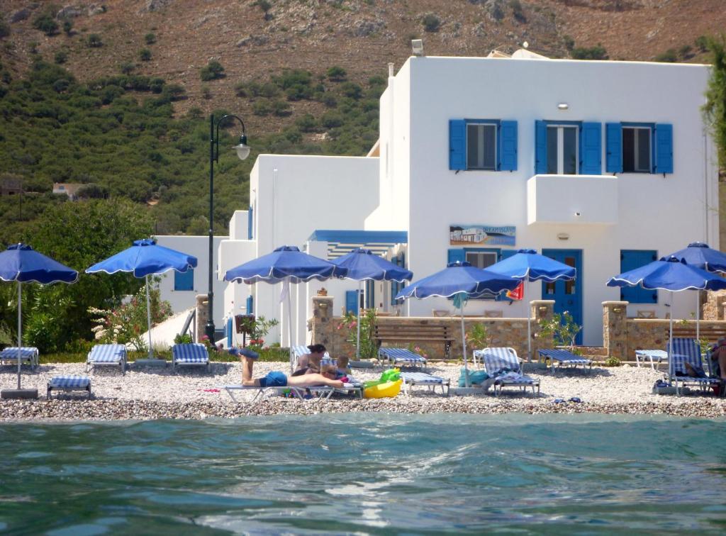 a person on a beach with blue umbrellas and the water at Dream Island Hotel in Livadia