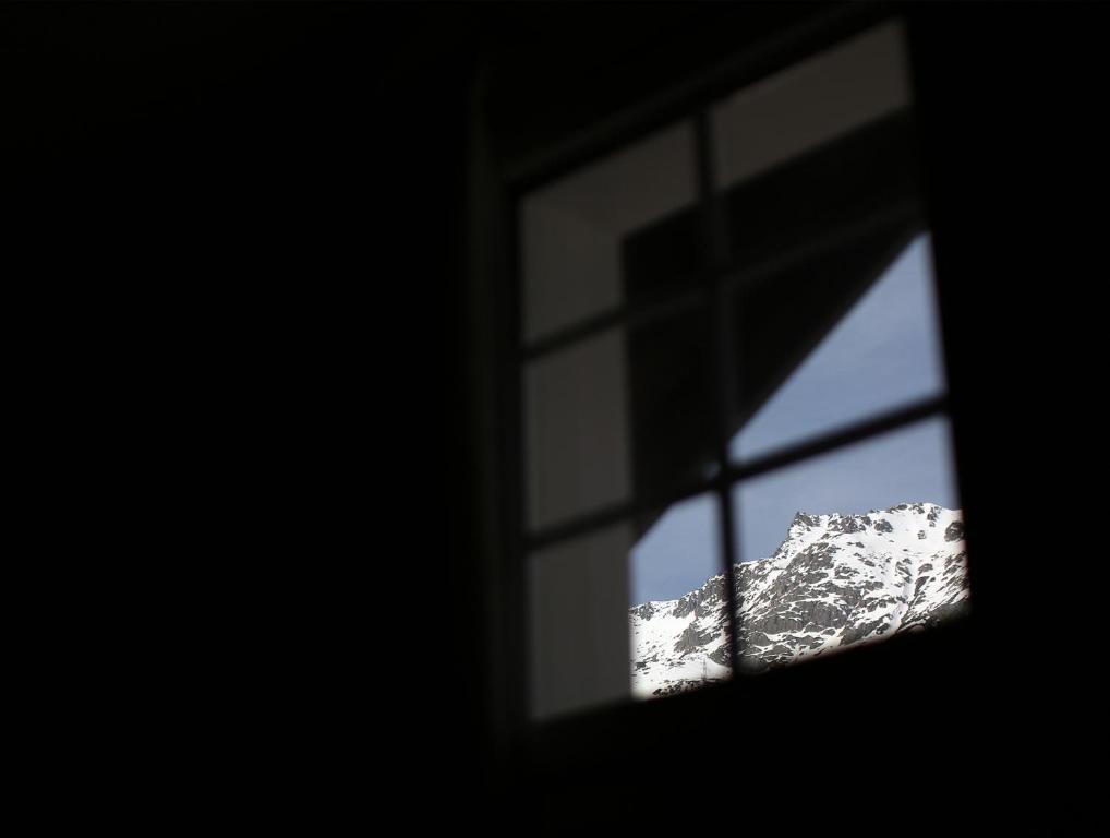 a view of a snow covered mountain through a window at Chalet Swiss Andermatt in Andermatt