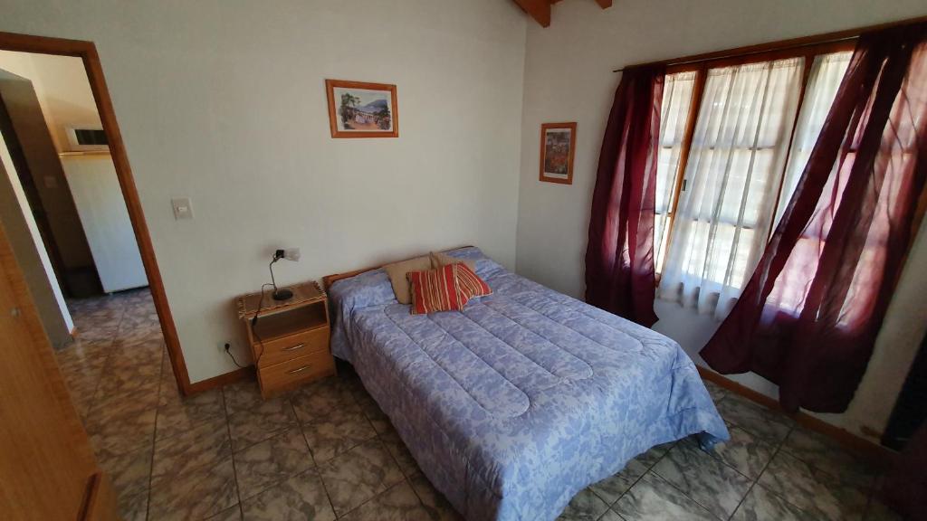 a bedroom with a bed and a dresser and a window at Casita Fontanive in San Martín de los Andes