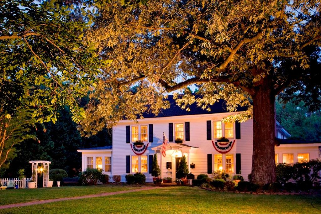 une maison blanche avec un arbre en face dans l'établissement A Williamsburg White House Inn, à Williamsburg