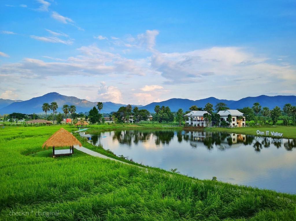 un pequeño lago en un campo con casas y montañas en Oon Valley Farm Stay, en Ban Mae Pha Haen