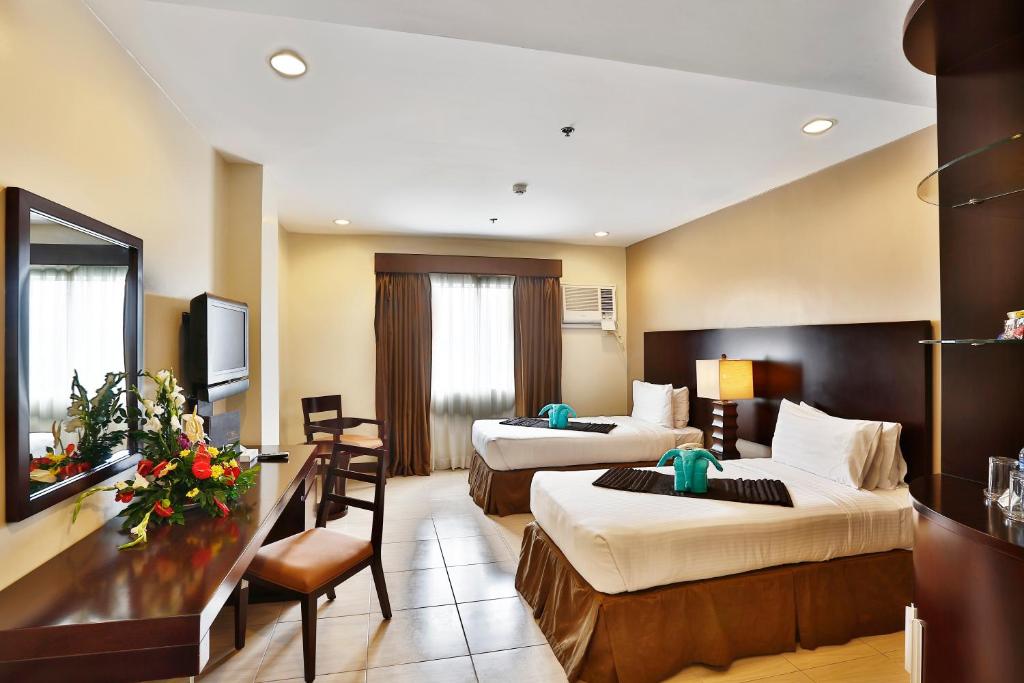 a hotel room with two beds and a desk at Alpa City Suites Hotel in Cebu City