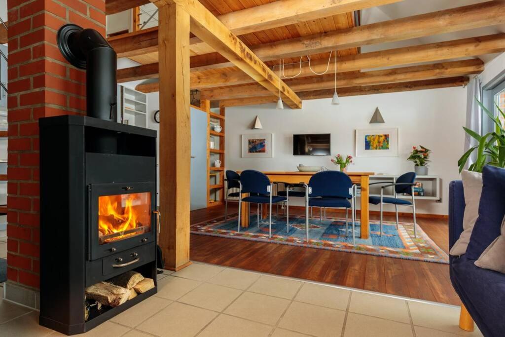a fireplace in a living room with a table and chairs at Modernes Landhaus mit Sauna in Hohen Pritz