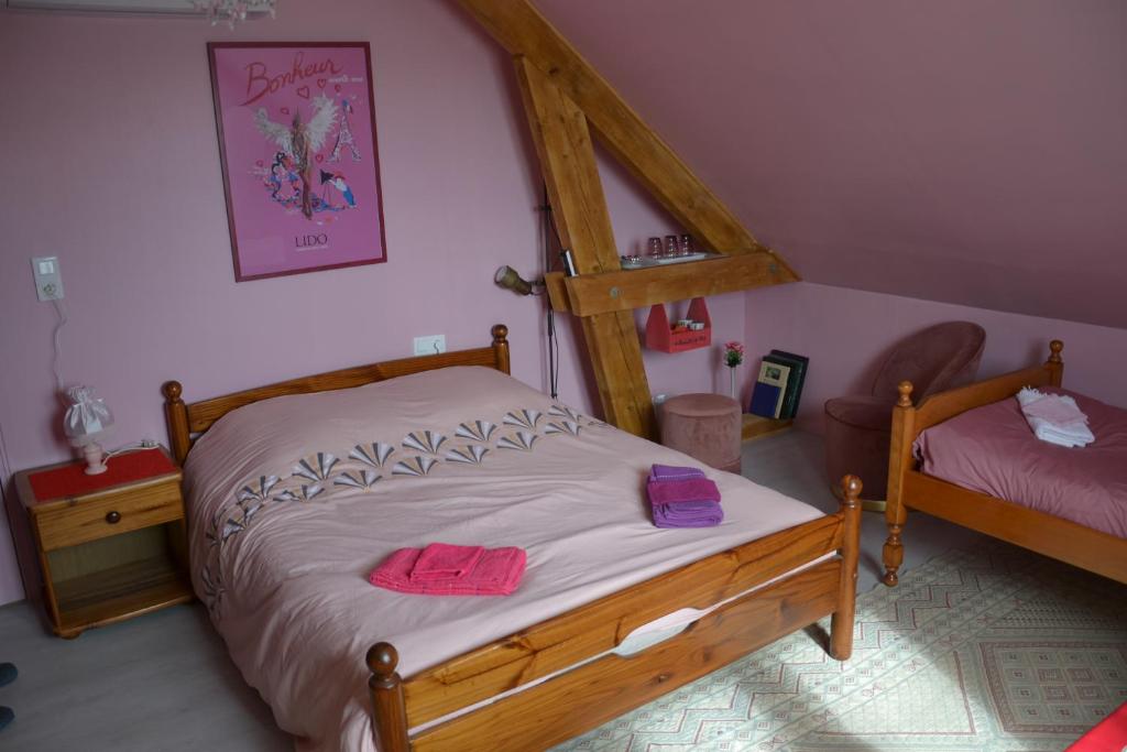 a bedroom with a wooden bed with pink towels on it at Les Talents Aiguilles in Breuil-sur-Vesle