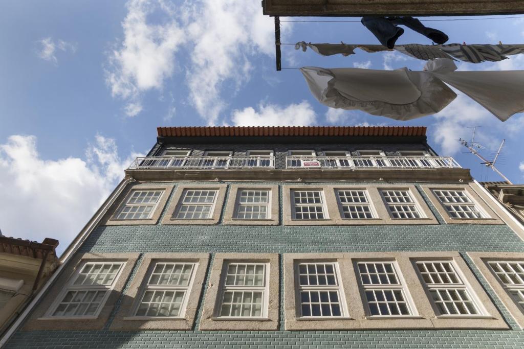 ein hohes Gebäude mit weißen Fenstern davor in der Unterkunft MSC Flats - Comercio do Porto in Porto