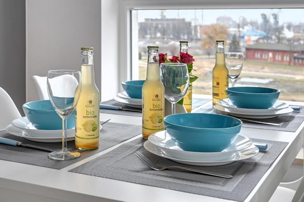 a table with plates and wine bottles on it at Apartament Bastion Sky Gdańsk TriApart in Gdańsk