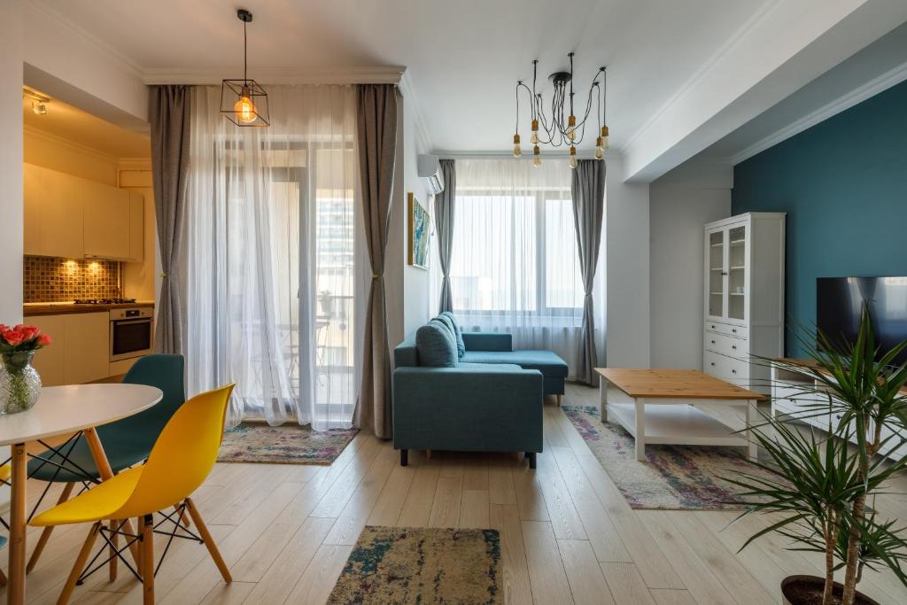 - un salon avec un canapé bleu et une table dans l'établissement Mayor Apartment Faleza Nord, à Constanţa