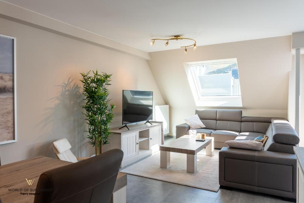 een woonkamer met een bank en een tv bij Spacious apartment in the heart of Ostend near the sea in Oostende