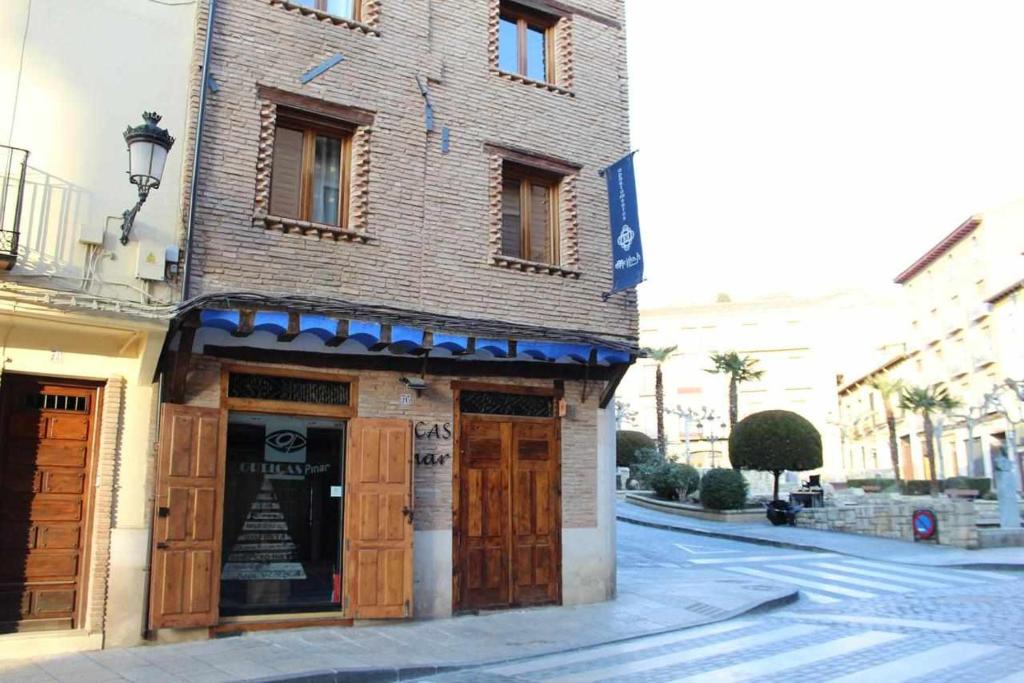 un edificio de ladrillo con puertas de madera en una calle en Hotel Apartamentos Melihah en Daroca