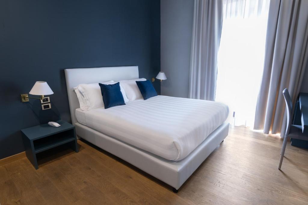 a bedroom with a large white bed with blue pillows at Hotel Enzo in Porto Recanati