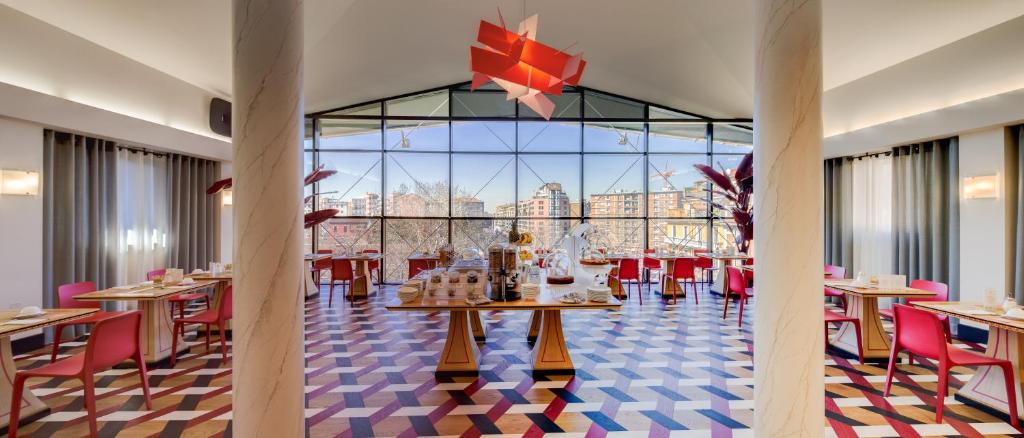restauracja ze stołami i krzesłami oraz dużym oknem w obiekcie c-hotels Rubens w Mediolanie