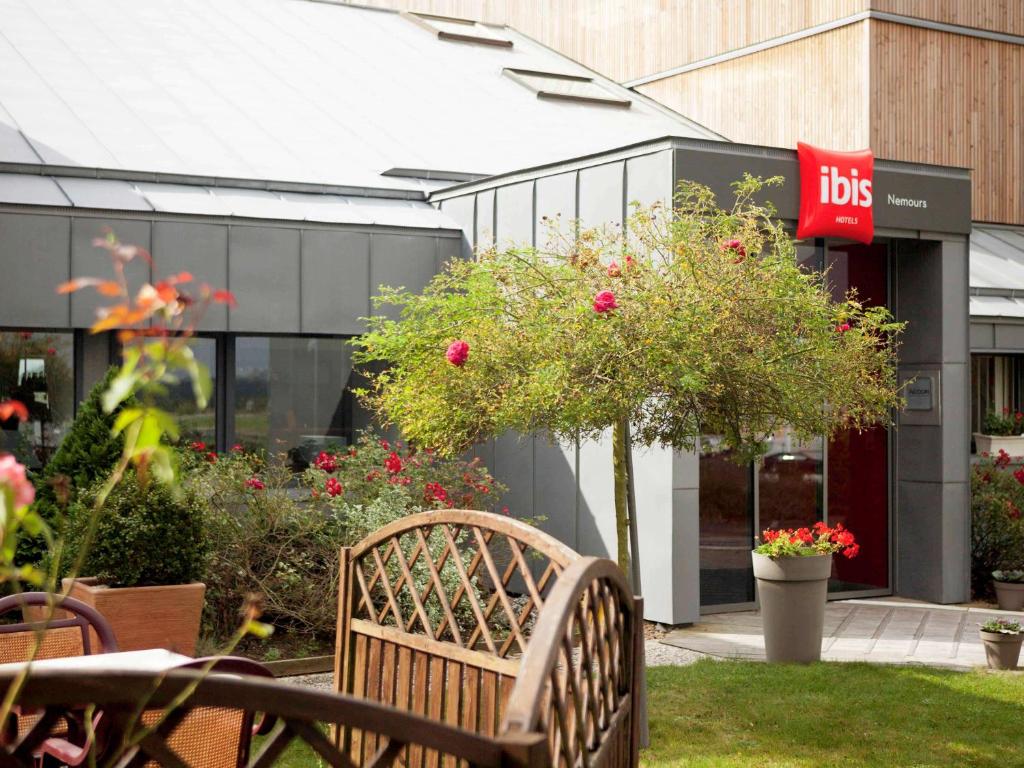 un banc assis devant un bâtiment fleuri dans l'établissement ibis Nemours, à Nemours