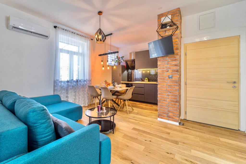 a living room with a blue couch and a kitchen at Apartman Letifico in Split