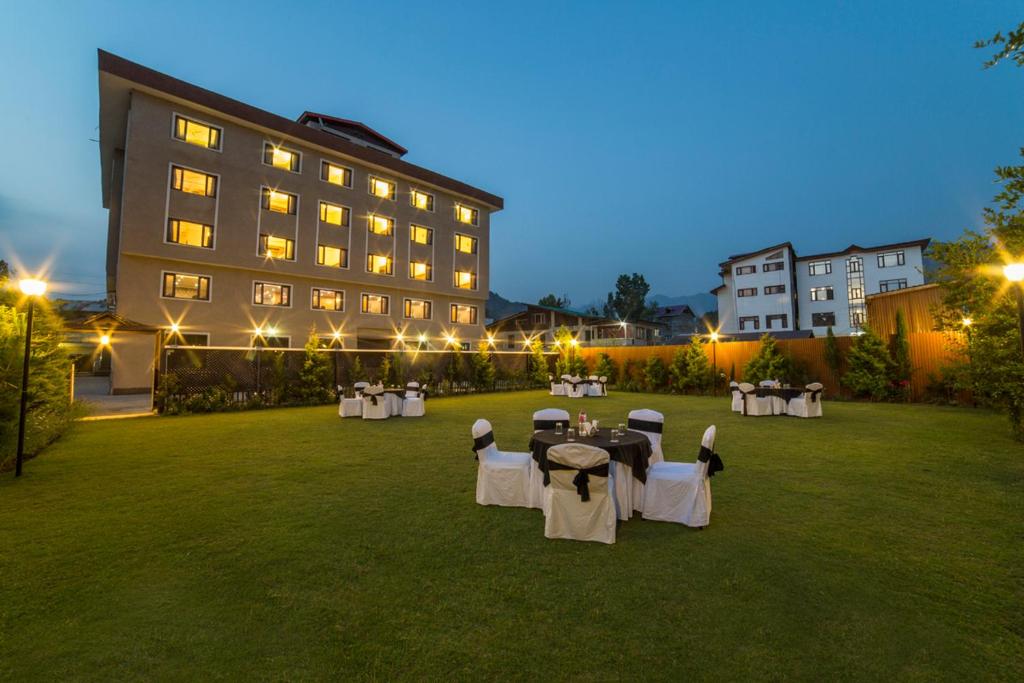 a lawn with tables and chairs in front of a building at Hotel Solar Residency in Srinagar