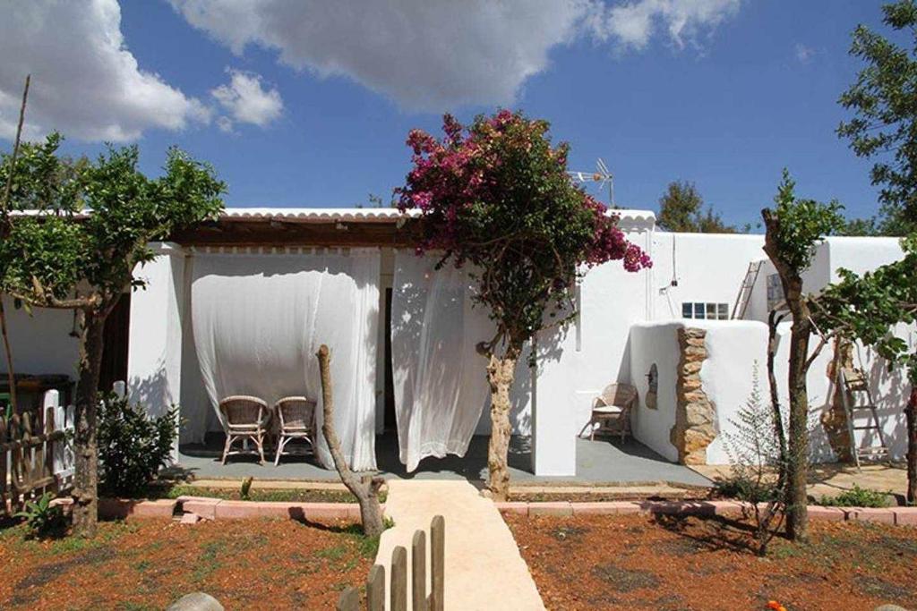 een wit huis met een tafel en stoelen in een tuin bij Agroturismo Casa Morna Ibiza in Sant Carles de Peralta