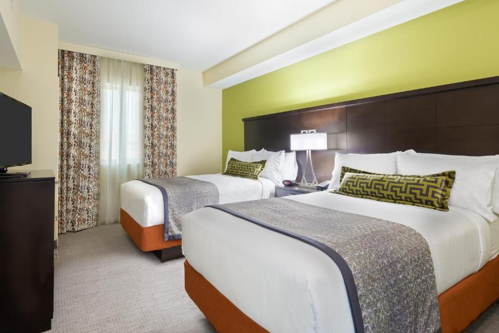 a hotel room with two beds and a television at Staybridge Suites - Miami International Airport by IHG in Miami