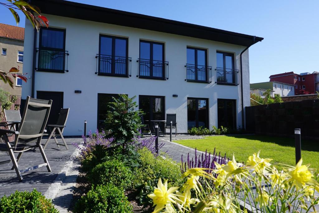 Hanse-City-Boardinghouse في غرايفسفالد: منزل به نوافذ سوداء وكراسي في حديقة