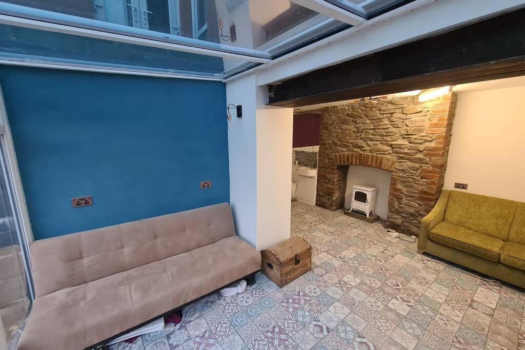 ein Wohnzimmer mit einem Sofa und einem Steinkamin in der Unterkunft Apartment near Brecon Beacons and Bike Park Wales in Bedlinog
