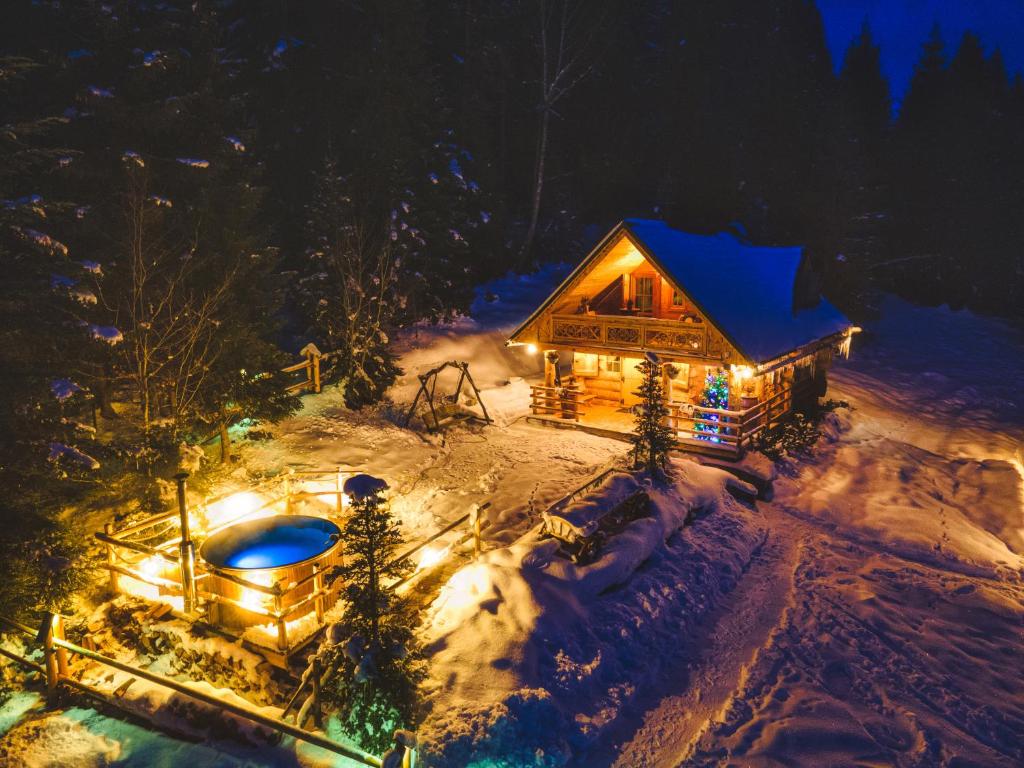 a log cabin with lights in the snow at night at Leśna Bacówka in Nowy Targ