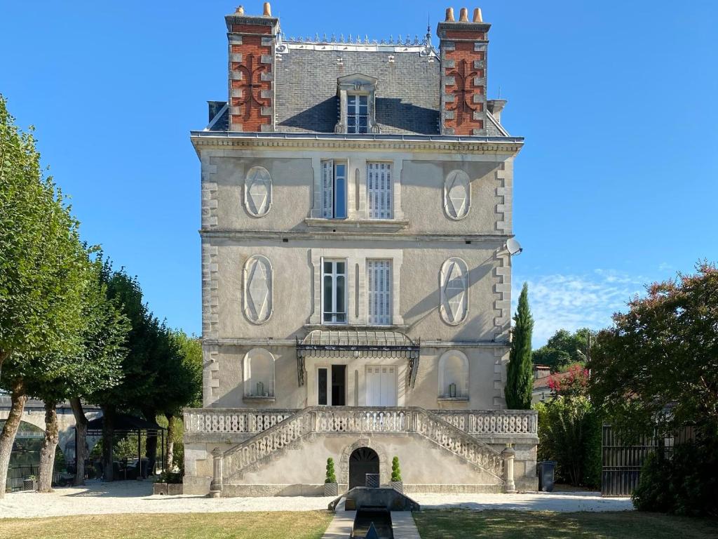 a building with a tower with a fountain in front of it at Stunning Chateau on the river bank in Saint Astier in Saint-Astier