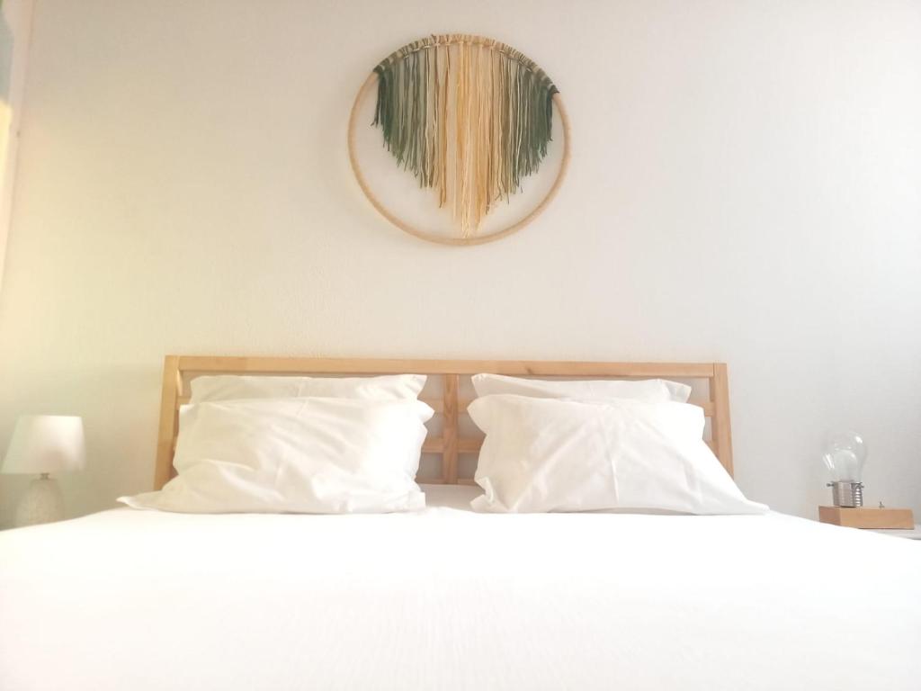 a bed with white pillows and a mirror on the wall at Troia Beach Getaway in Troia