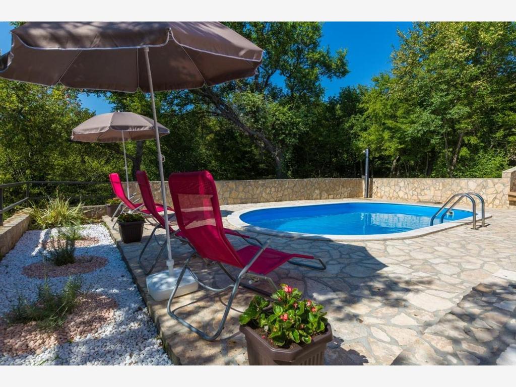 two chairs and an umbrella next to a swimming pool at GOMERCIC in Grižane