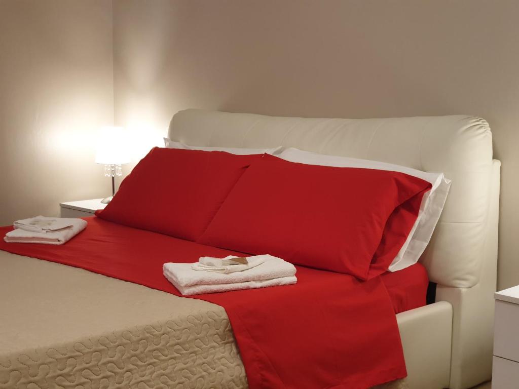 a bed with red pillows and a red blanket at Oasi Iblea Inn in Ragusa