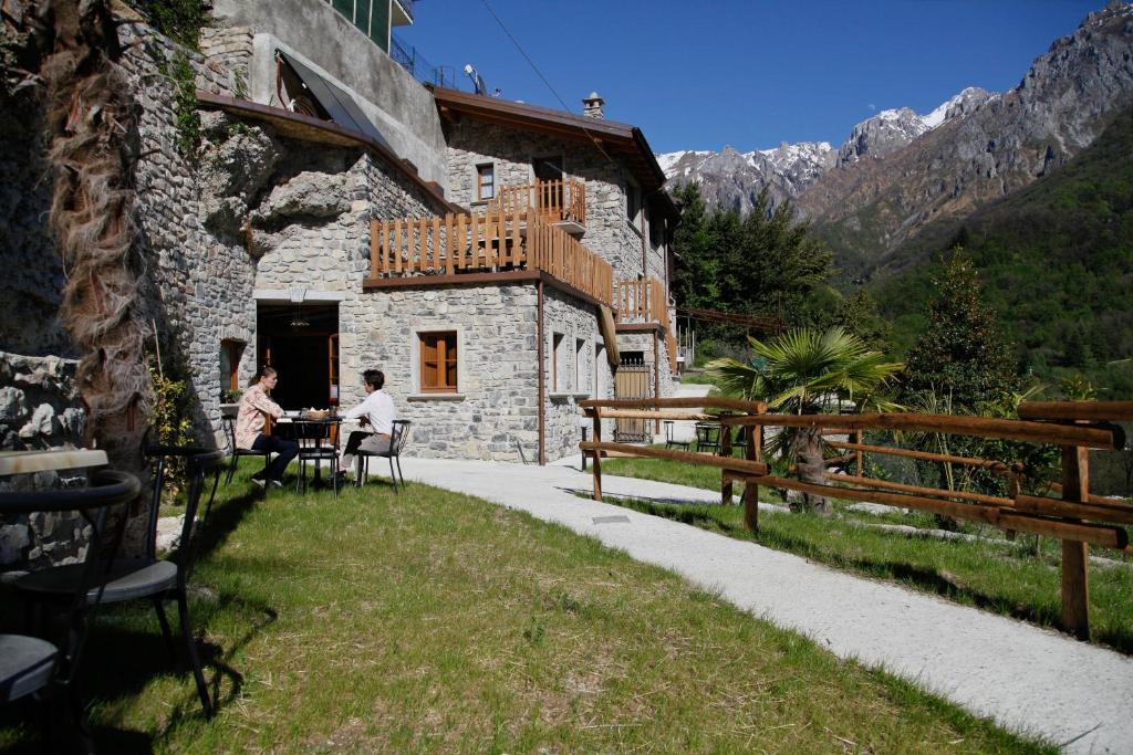 dos personas sentadas en una mesa fuera de un edificio en Agriturismo Crotto Di Somana, en Mandello del Lario