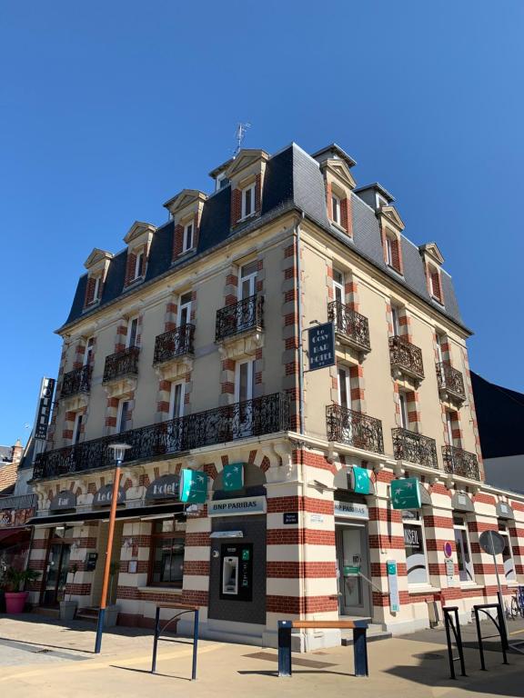 a large building on the corner of a street at Hotel Le Cosy Riva Bella in Ouistreham