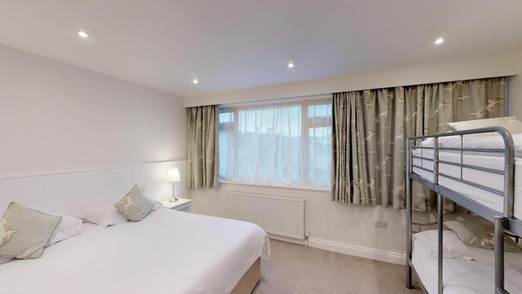a white bedroom with a bunk bed and a window at Ommaroo Hotel in Saint Helier Jersey